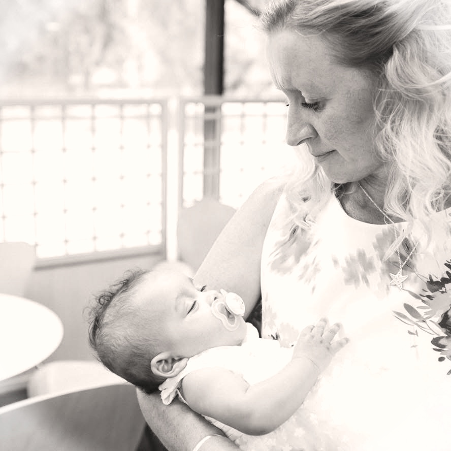Judith Baxter, doula, tenderly holding a newborn baby